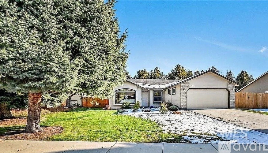 A house with a garage and a tree in front of it.