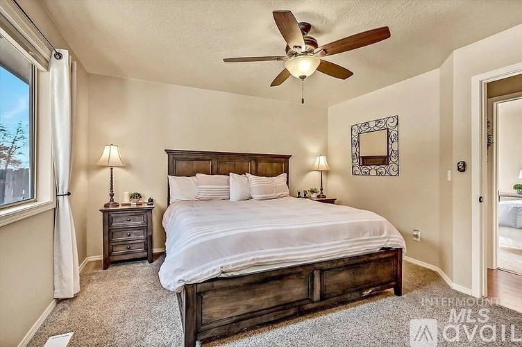 A bedroom with a bed, nightstand, and a ceiling fan.
