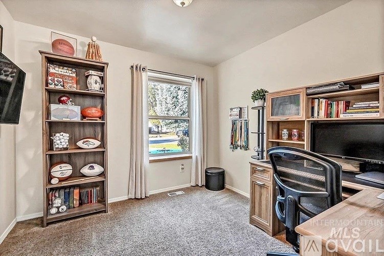 A room with a large window, a desk, and a bookshelf filled with books and sports memorabilia.