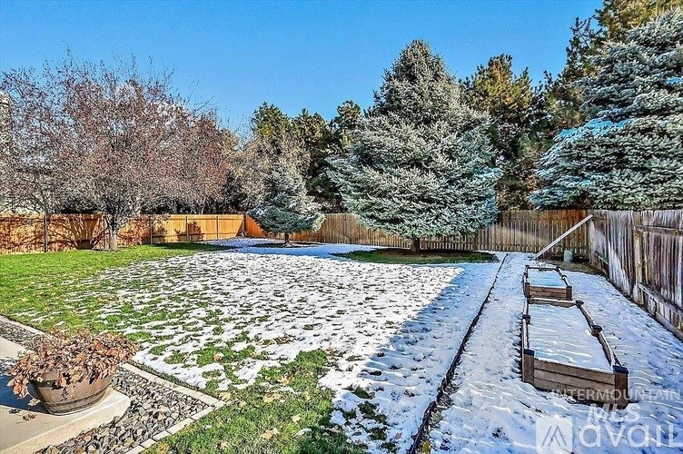 A backyard with a snow-covered ground and a wooden fence.