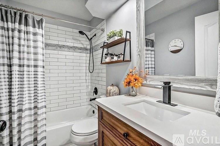 A bathroom with a white sink, a white toilet, a white bathtub, a white shower curtain, a wooden shelf, a clock, and a vase with orange flowers.