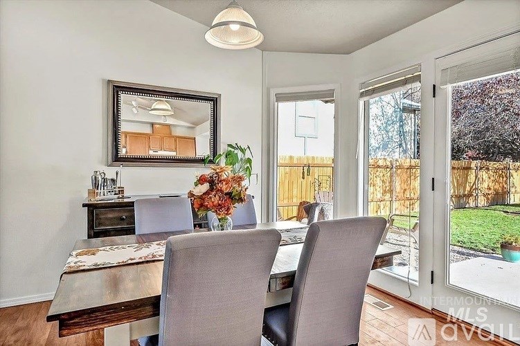 A dining room with a table and chairs and a view of a backyard.