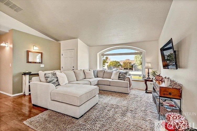 A living room with a white couch and a grey rug.
