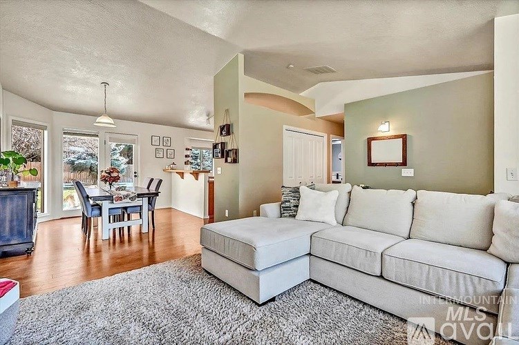A living room with a white couch and a grey rug.