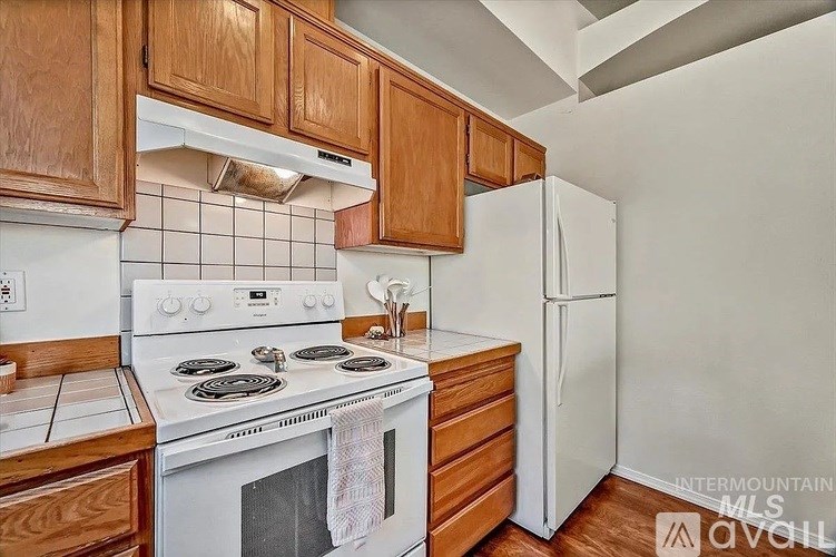 A kitchen with a white stove top oven and white refrigerator.