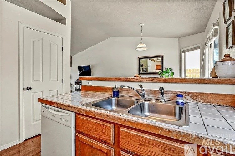 A kitchen with a white dishwasher and a double sink.