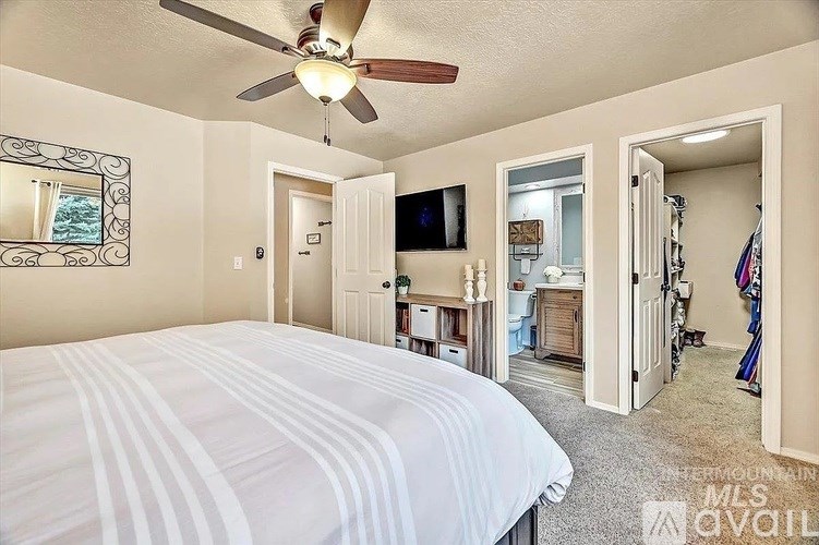 A bedroom with a large bed and a ceiling fan.