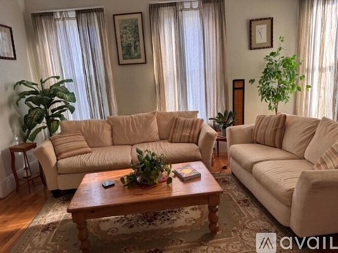 A living room with a large sectional sofa, a loveseat, and a coffee table with a plant and a book on it.