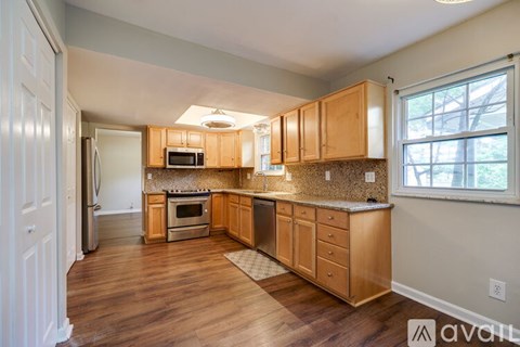 A kitchen with wooden cabinets and a stainless steel refrigerator.