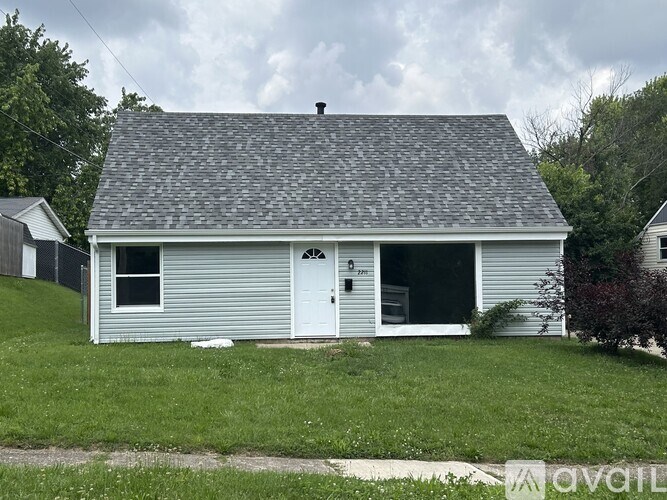 A small house with a white door and a grey roof.