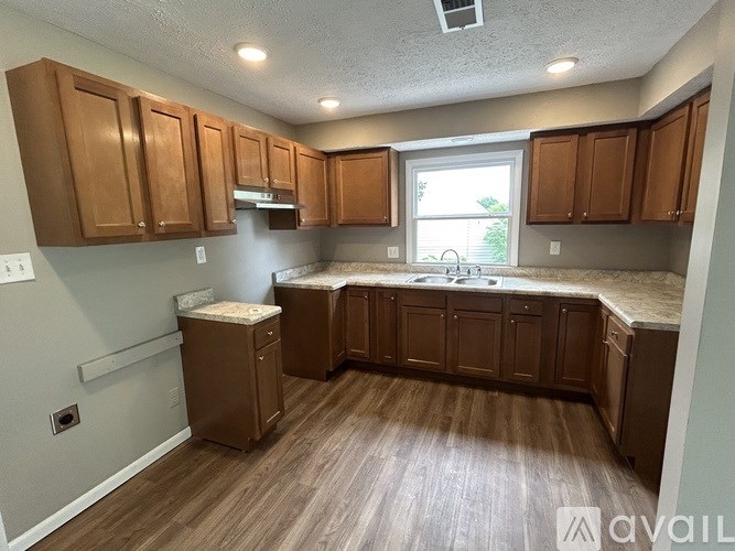 A kitchen with brown cabinets and a window.
