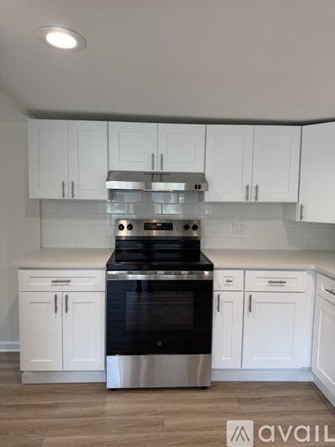 A modern kitchen with white cabinets and a stainless steel stove top.