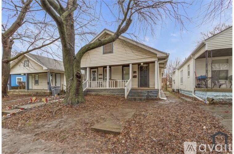 A house with a front yard and a tree in the foreground.