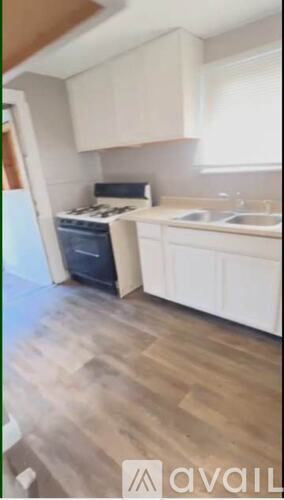 A kitchen with white cabinets and a wooden floor.