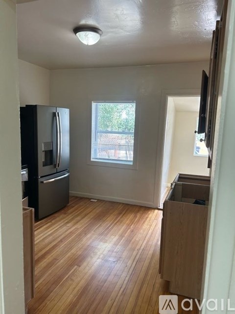 A kitchen with a refrigerator and wooden floors.