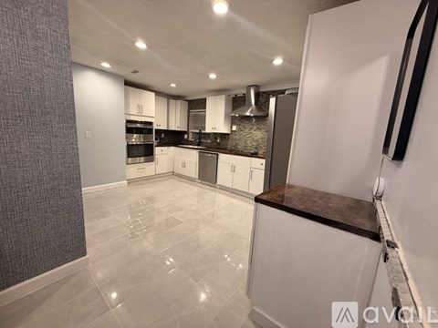 A modern kitchen with white cabinets and a wooden countertop.