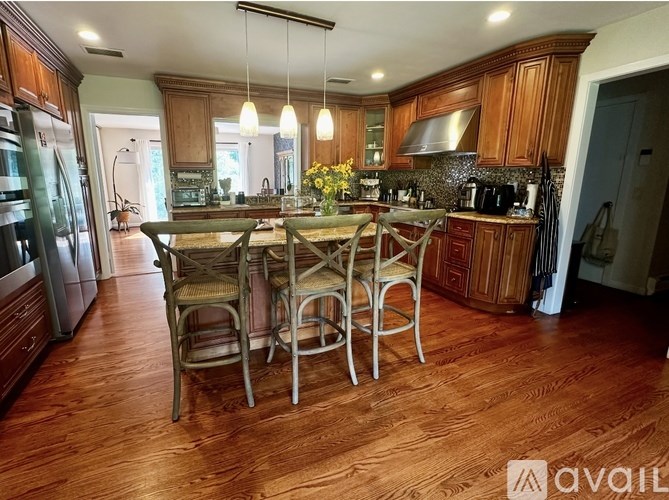 A kitchen with wooden floors and a center island with chairs.