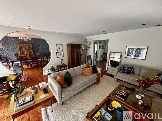 A living room with a grey couch and a coffee table with a vase of flowers on it.