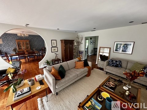 A living room with a grey couch and a coffee table with a vase of flowers on it.