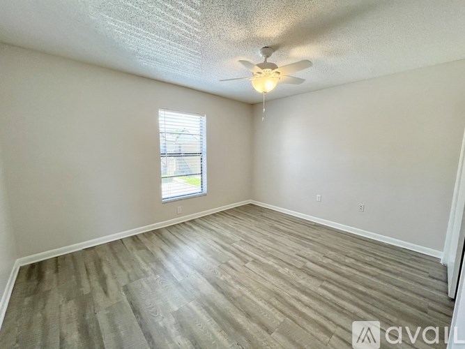 A spacious room with wooden flooring and white walls.
