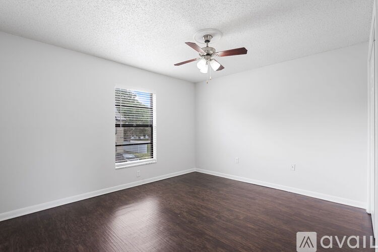 A room with a ceiling fan and a window with blinds.