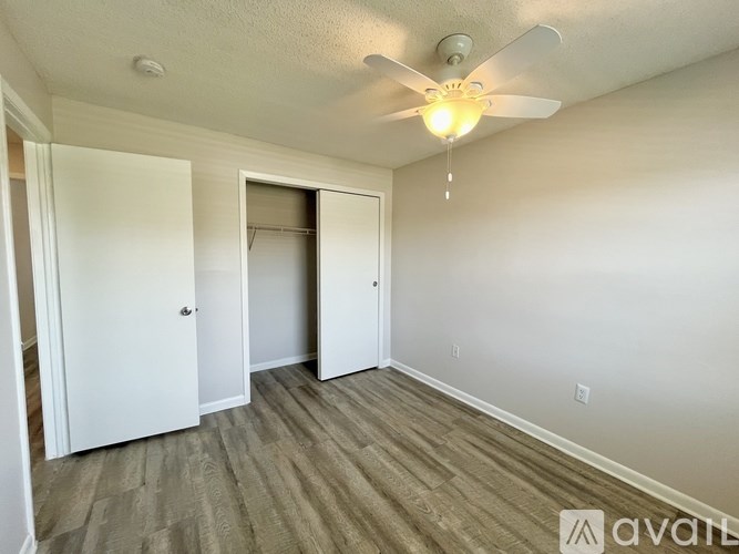 A blue dumpster is in front of a wooden fence and a small building.