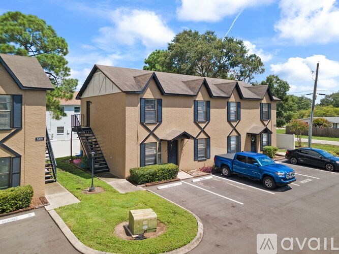 A blue truck is parked in front of a building with a sign that reads "AVAIL".