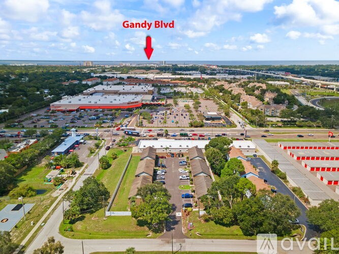 An aerial view of a shopping center with a red arrow pointing to Gandy Blvd.