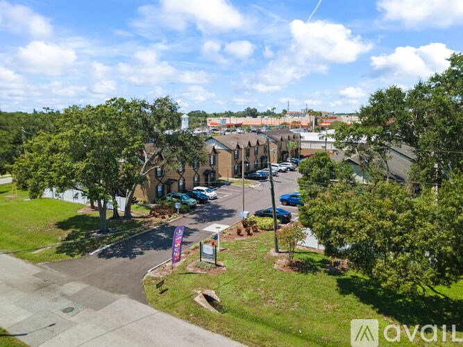 A sunny day in a residential area with apartment buildings and cars parked in the driveways.