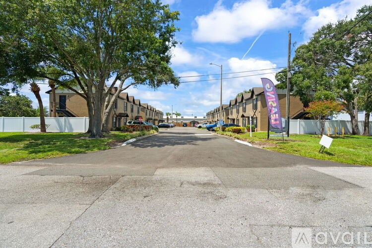 A street view of a residential area with houses on both sides and a sign that reads "Avail".