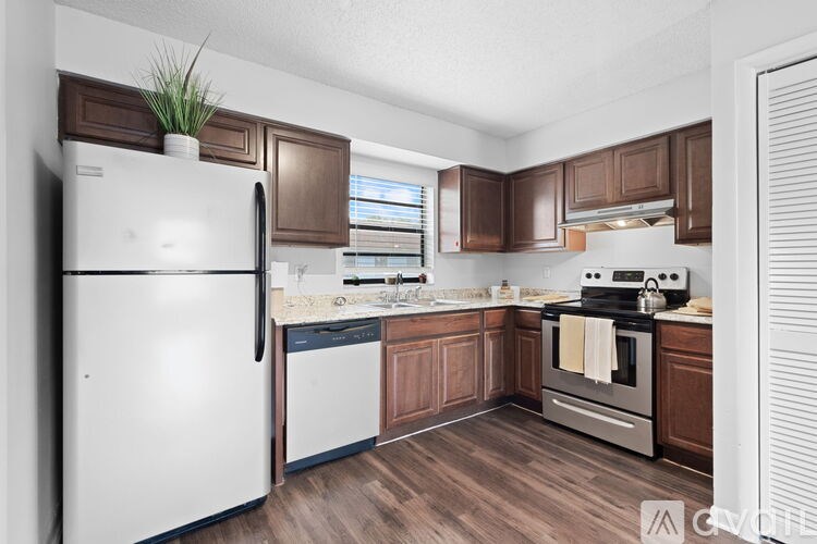 A kitchen with a white fridge and brown cabinets.