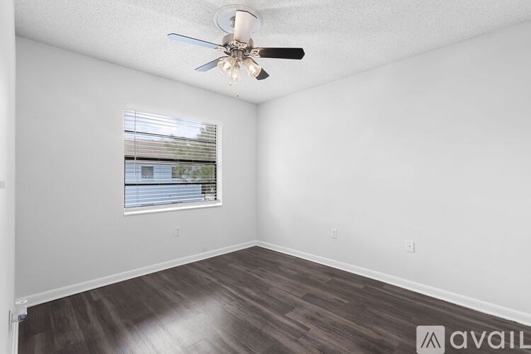 A room with a ceiling fan and a window with blinds.