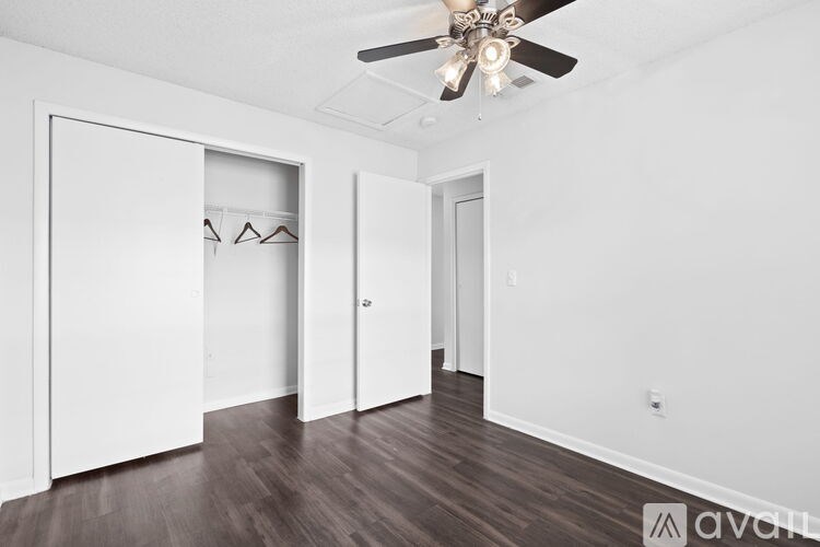 A room with a ceiling fan and a door on the left.
