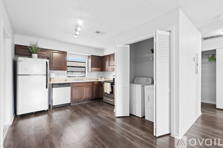 A kitchen with white appliances and wooden floors.
