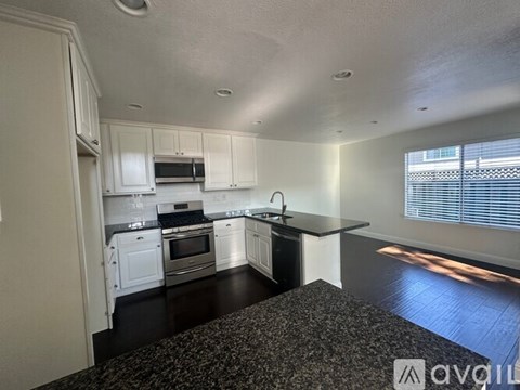 A kitchen with white cabinets and black countertops.
