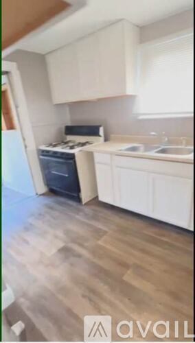 A kitchen with white cabinets and a wooden floor.