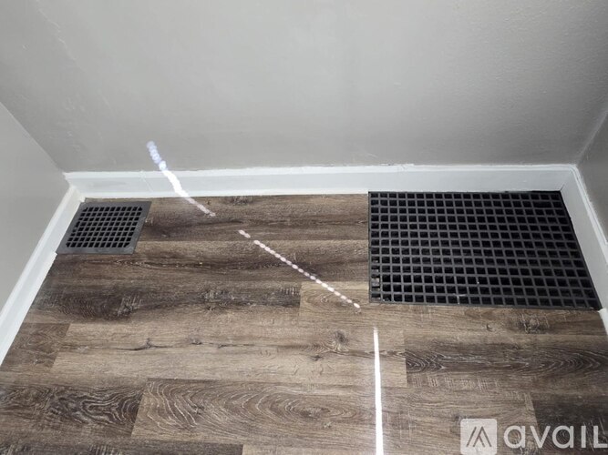 A room with a wooden floor and a metal grate.