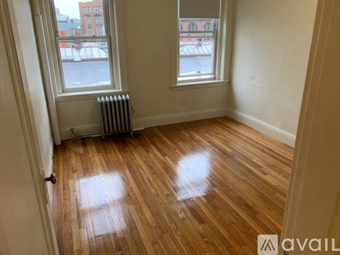 A room with wooden floors and two windows.