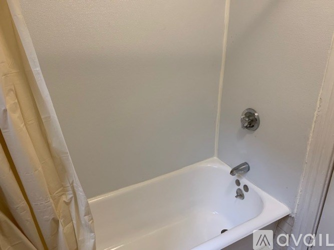 A white bathtub with a shower head and faucet.