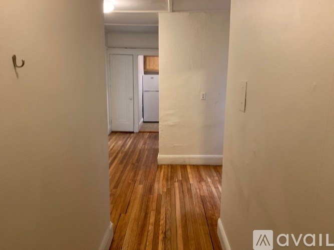 A hallway with wooden floors and white walls.