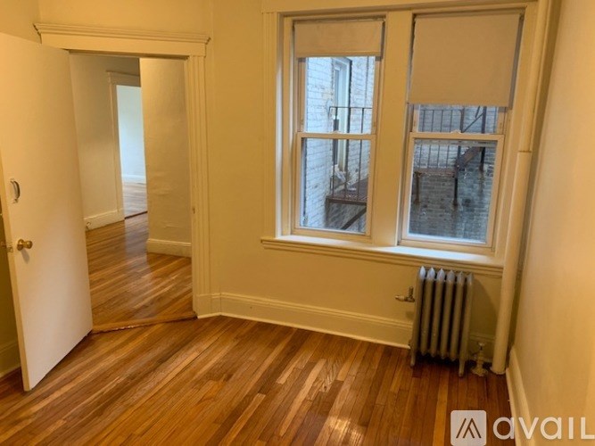 A room with a wooden floor and a window with a view of a balcony.