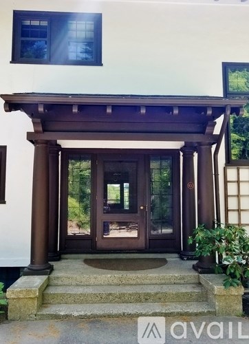 A large wooden cabinet with glass doors is in the middle of a room with a table and chairs.