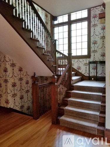 A room with wooden floors and furniture, including a wooden cabinet and a table with a vase of flowers on it.