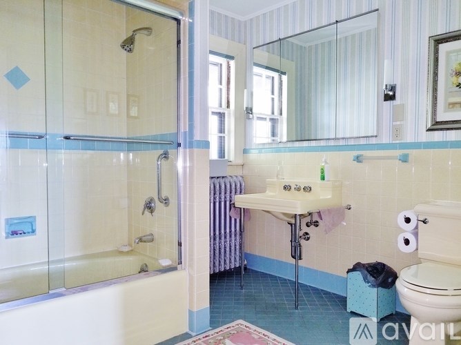 A large wooden cabinet with glass doors is in the middle of a room with a table and chairs.