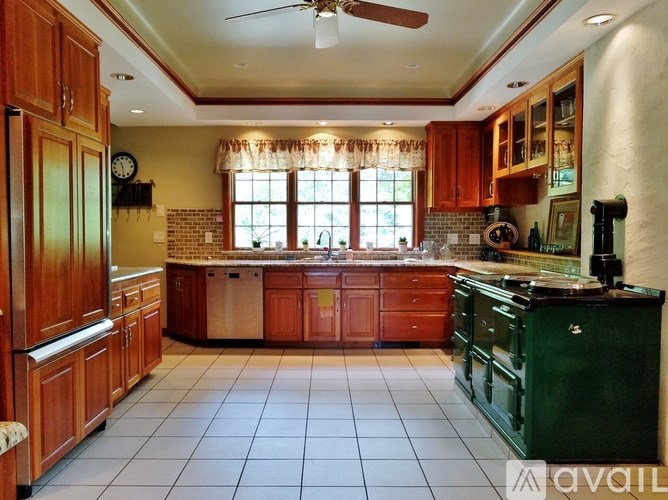 A room with wooden floors and furniture, a wallpapered wall, and a chandelier.