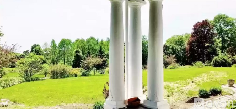 A white column stands in a lush green garden.