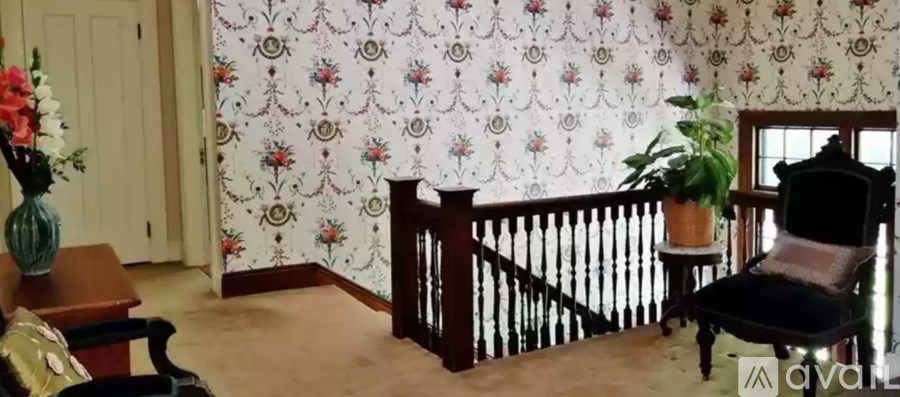 A room with a floral wallpaper and a wooden chair.