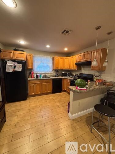 A kitchen with wooden cabinets and a black fridge.