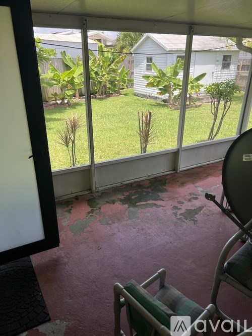 A room with a chair and a window overlooking a yard.