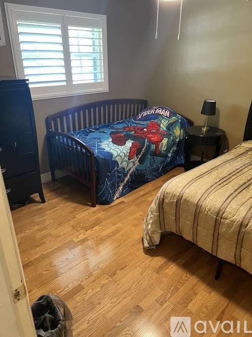 A bedroom with a bed covered in a comic book print sheet and a striped bedspread.